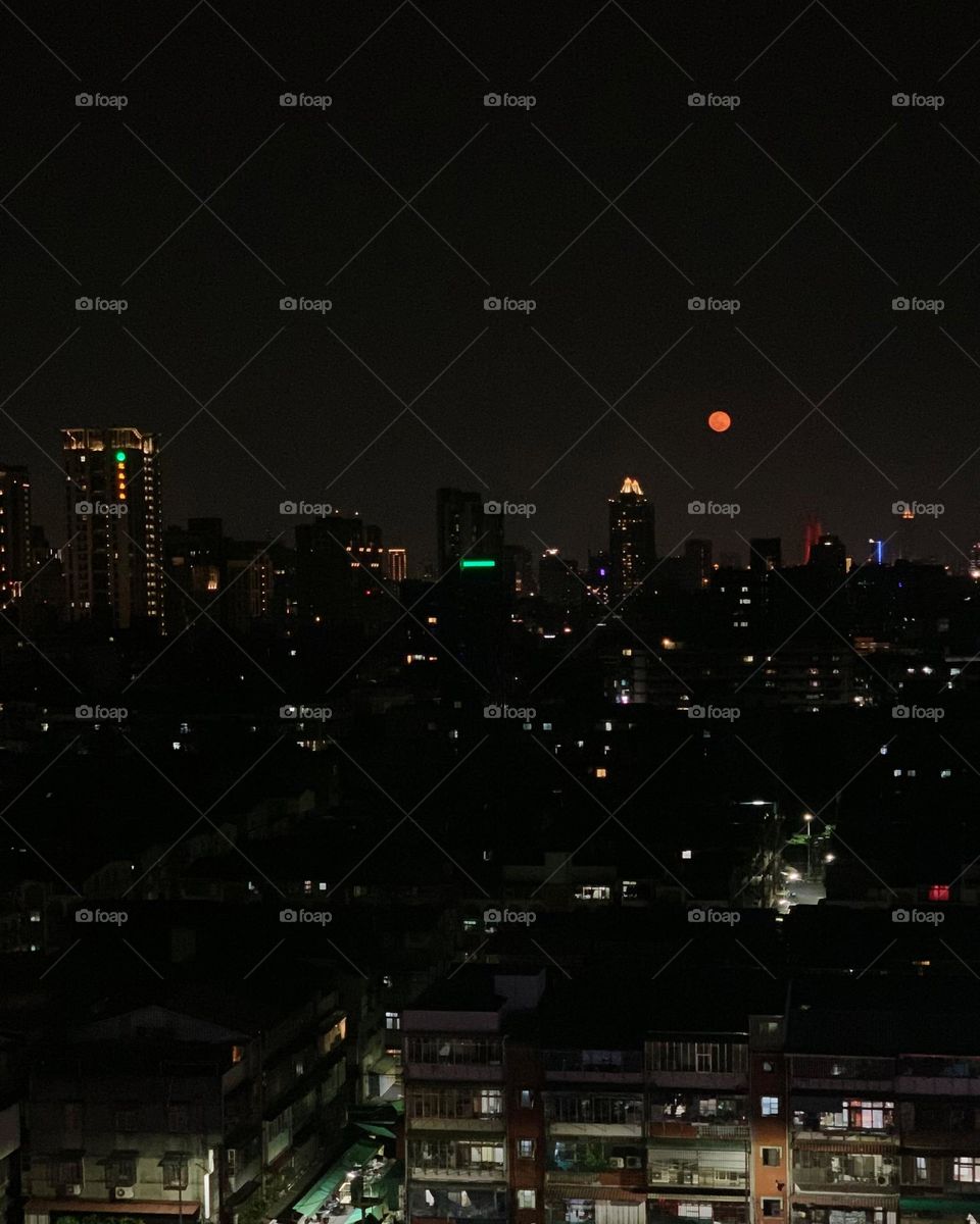Red moon with night city view