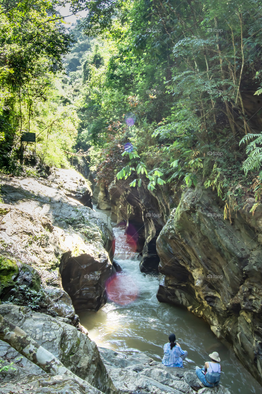 Tourists watch water flowing through the rocks are in a stream.