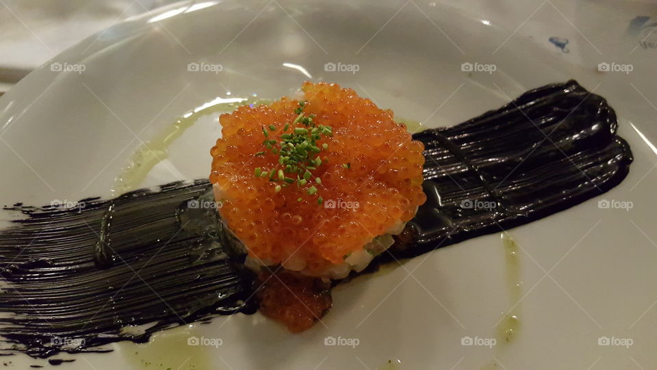 Sea bass tartare. with red caviar, served  on a dish with cuttlefish  black ink.