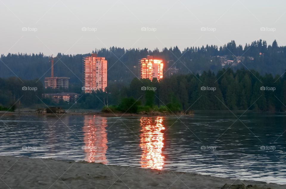 Sunset casting glow on high rises in ocean bay, Port Moody, British Columbia  