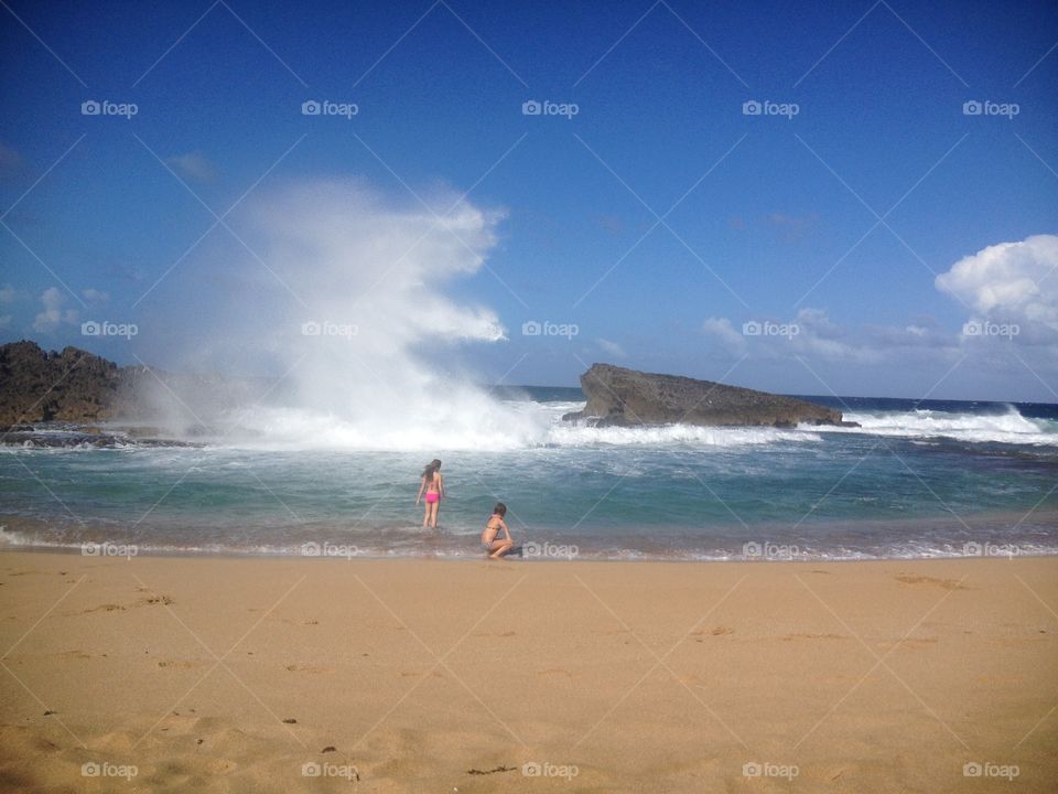 Puerto Rico beach with wave formations from rocks with kids playing in the foreground 