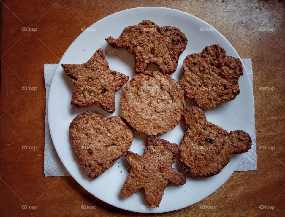 Matzo meal cookies, brown in a white round plate with brown background. Shaped cookies.