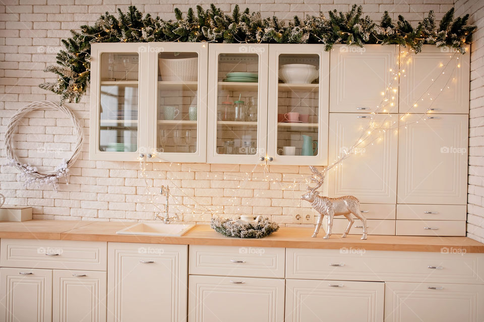 Festive winter cozy kitchen interior with garlands, decorations and gifts.  Christmas dinner at the decorated table.