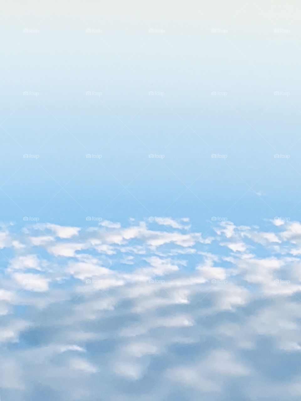 Inverted shot of striated colors of blue sky and stratus, popcorn clouds - portrait