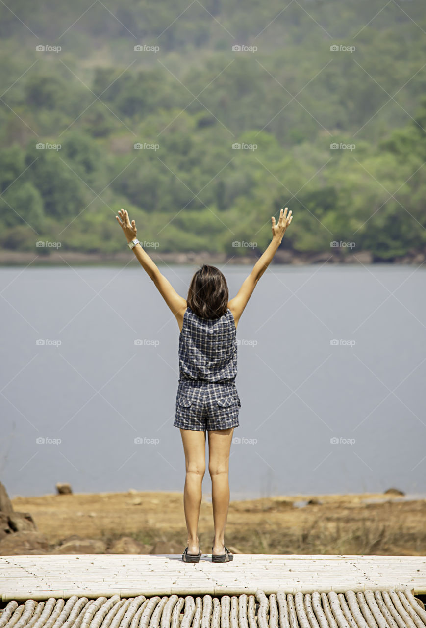 Women raise their arms Background mountains and water at Chakrabongse reservoir , Prachinburi in Thailand.