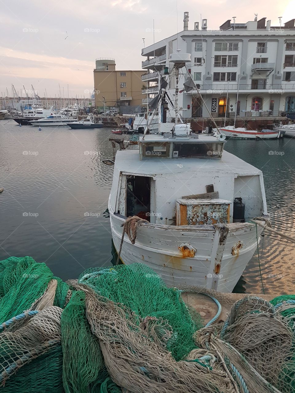 Boats and fish nets in the port of Genoa city at sunset