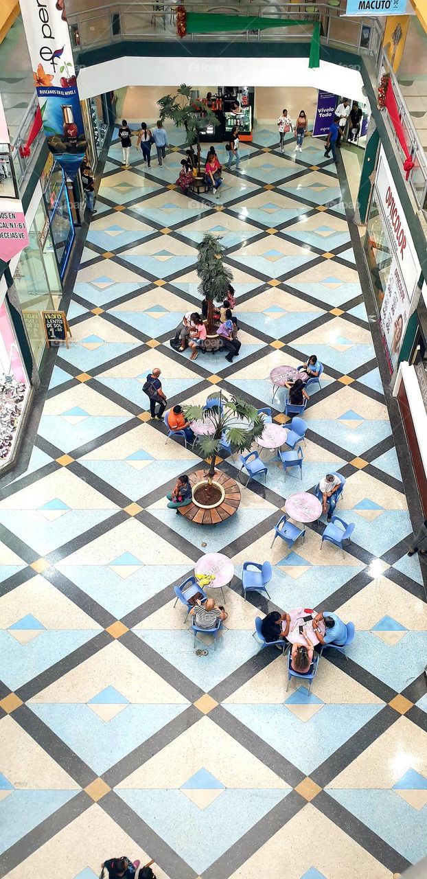 from above in the shopping center, admiring the decoration of the floor with blue details that match the chairs and its surroundings