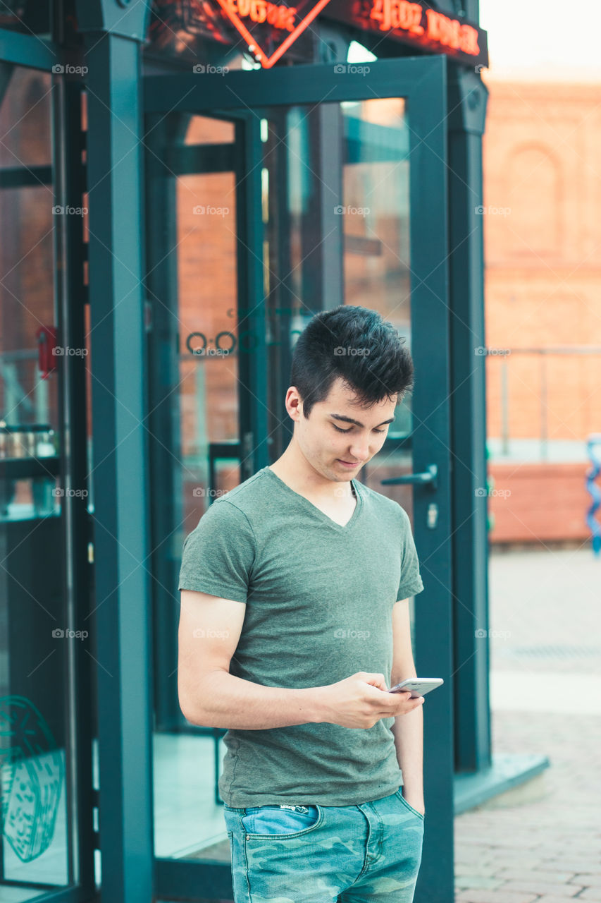 Young man using smartphone standing in center of town