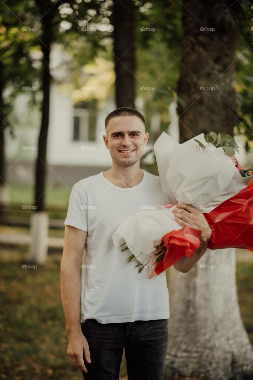 the young father holds bouquets of flowers given by the children for his birthday