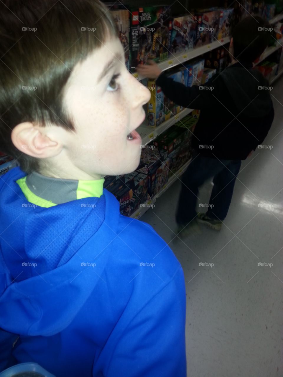 Seven year old boy at the store with a excited look on his face.