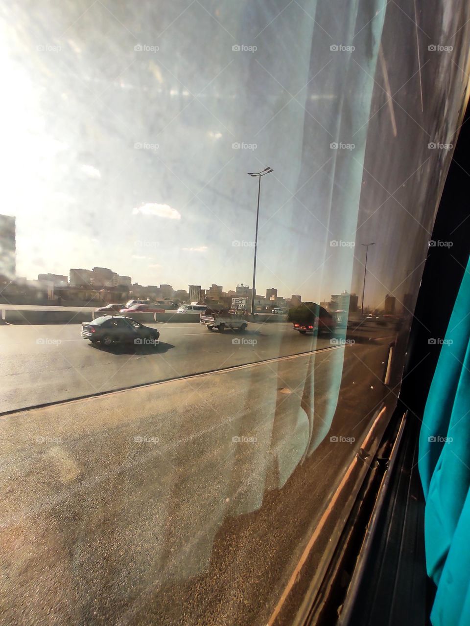 cars in the street from a window of bus abd reflections in the window