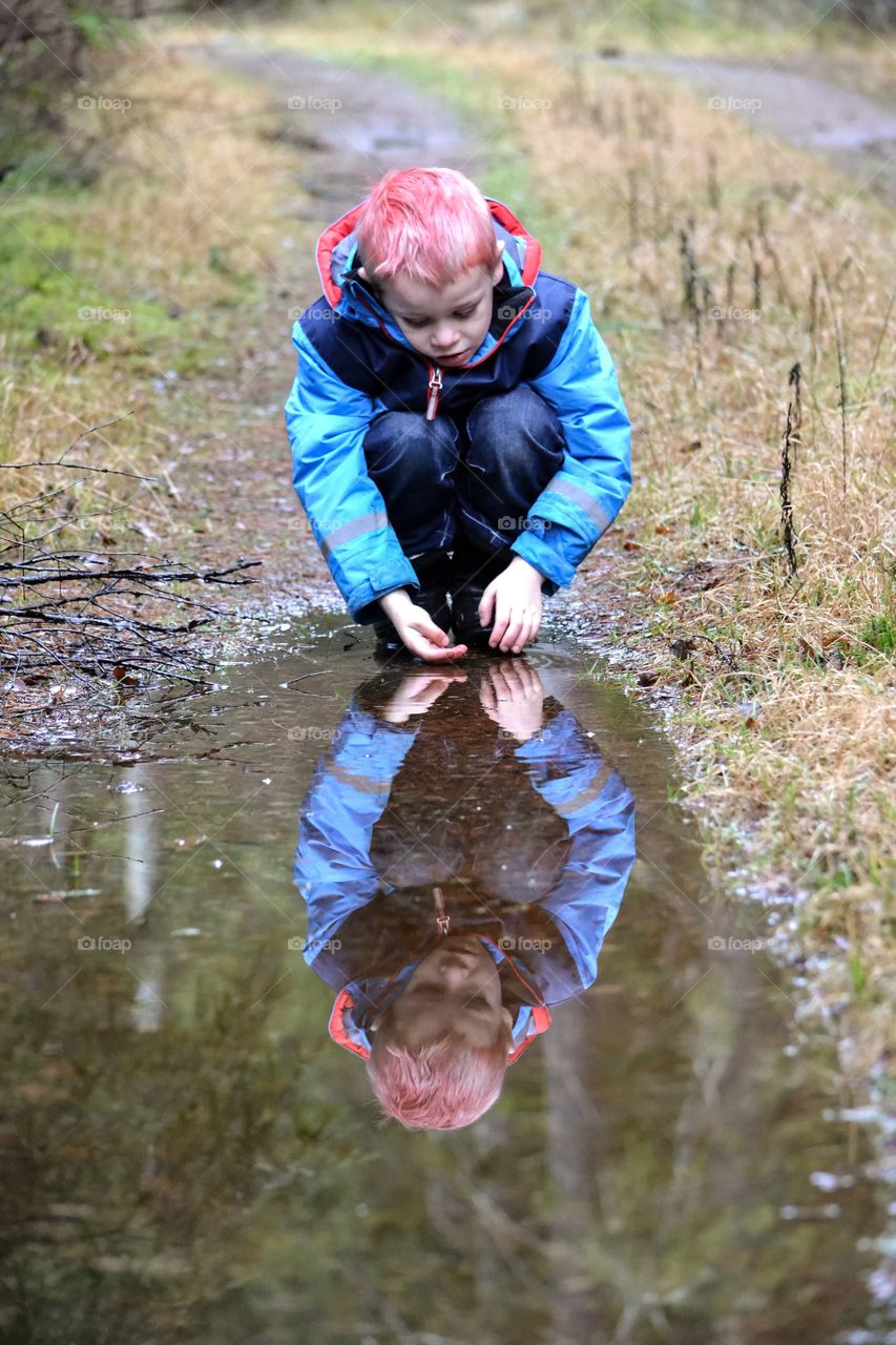 Little looking at his reflection in water