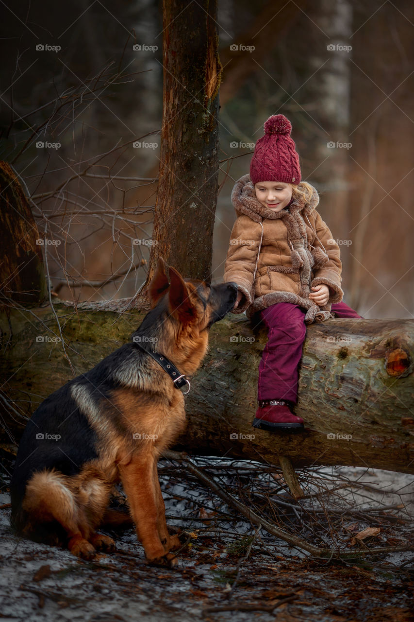 Little girl with German shepherd 6-th months puppy at early spring forest