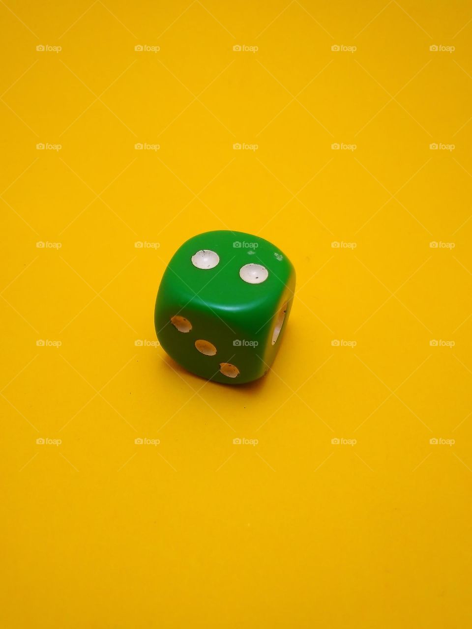 The green dice is a cube made of plastic with a white dot on each side indicating the number of digits.