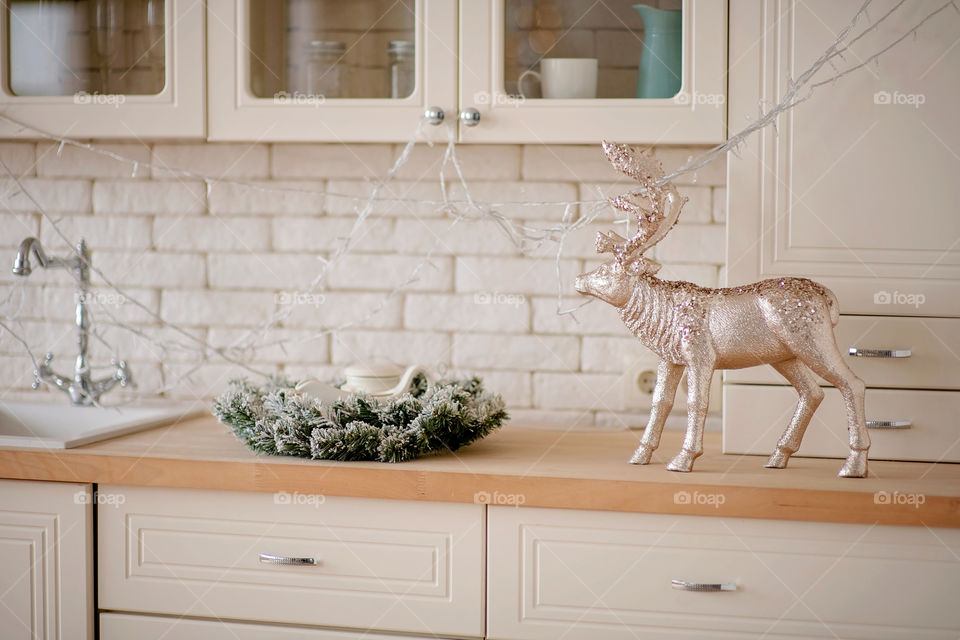 Festive winter cozy kitchen interior with garlands, decorations and gifts.  Christmas dinner at the decorated table.