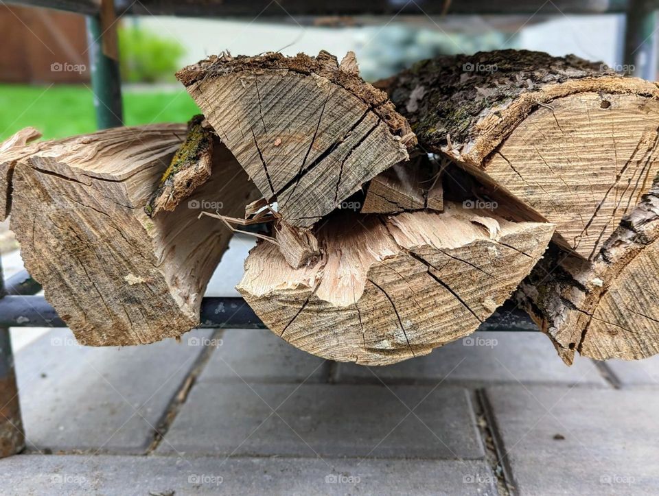 split firewood stacked up by the fire pit on the patio, dry fire wood stacked up ready for a bonfire