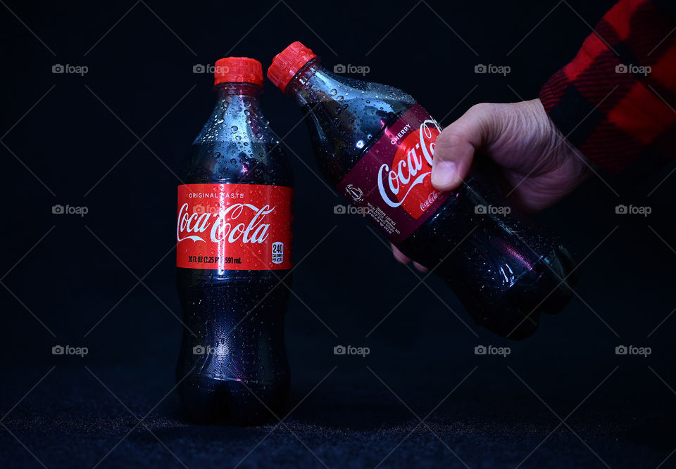 Close up shot of two Coca Cola with black background with the mists at the studio.  