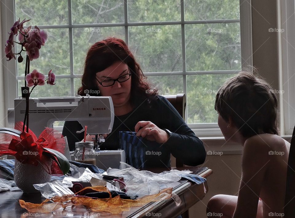 Using A Sewing Machine. Mother Sewing A Costume For Her Son
