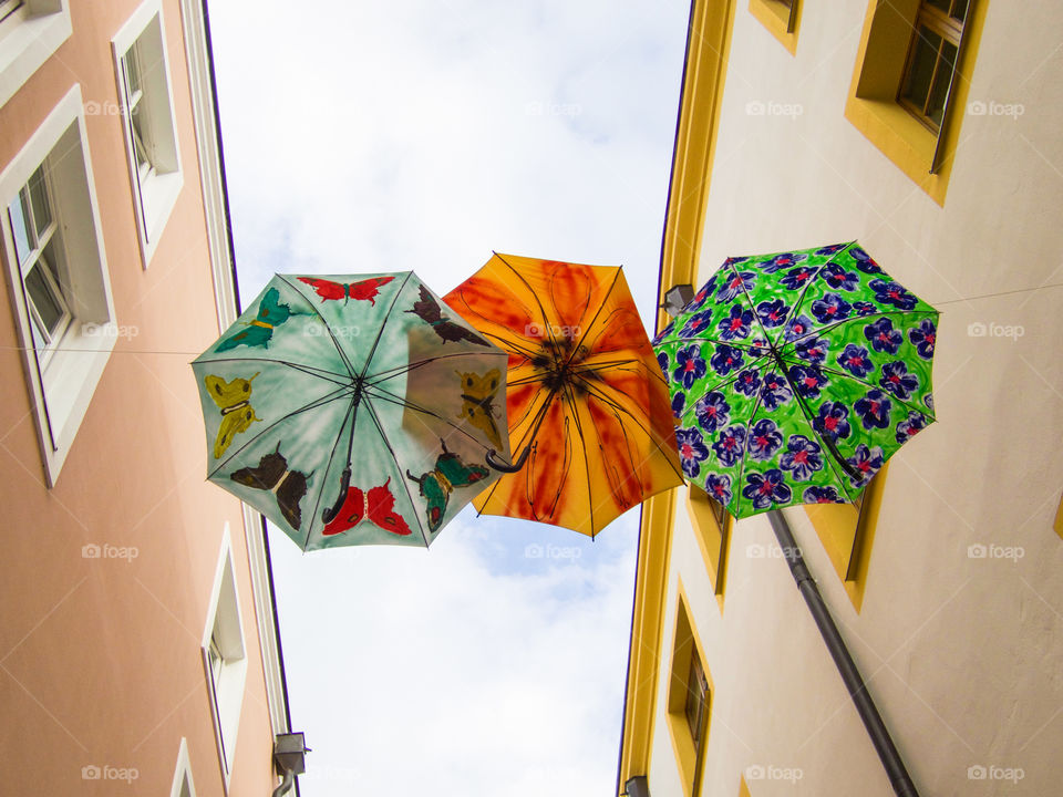 Three umbrellas. Three umbrellas high above the street. 