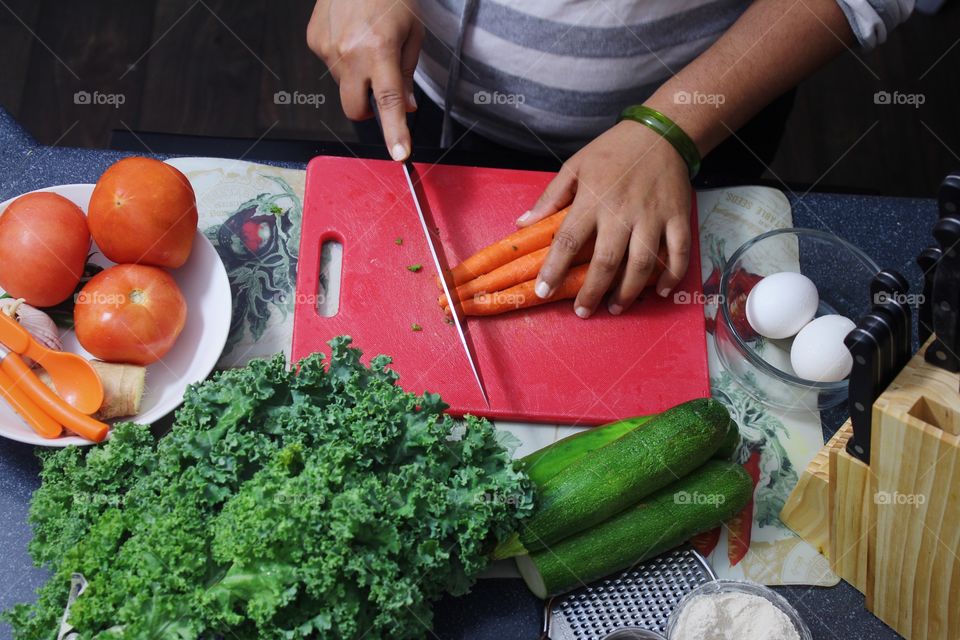 Young woman working cutting carrot in kitchen