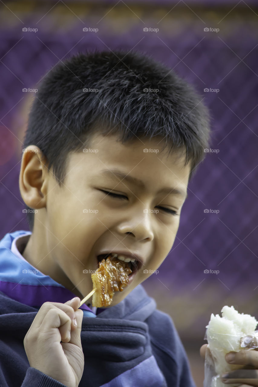 Asian boys are eating sticky rice and pork roast , The food is simple and popular to eat breakfast in Thailand.