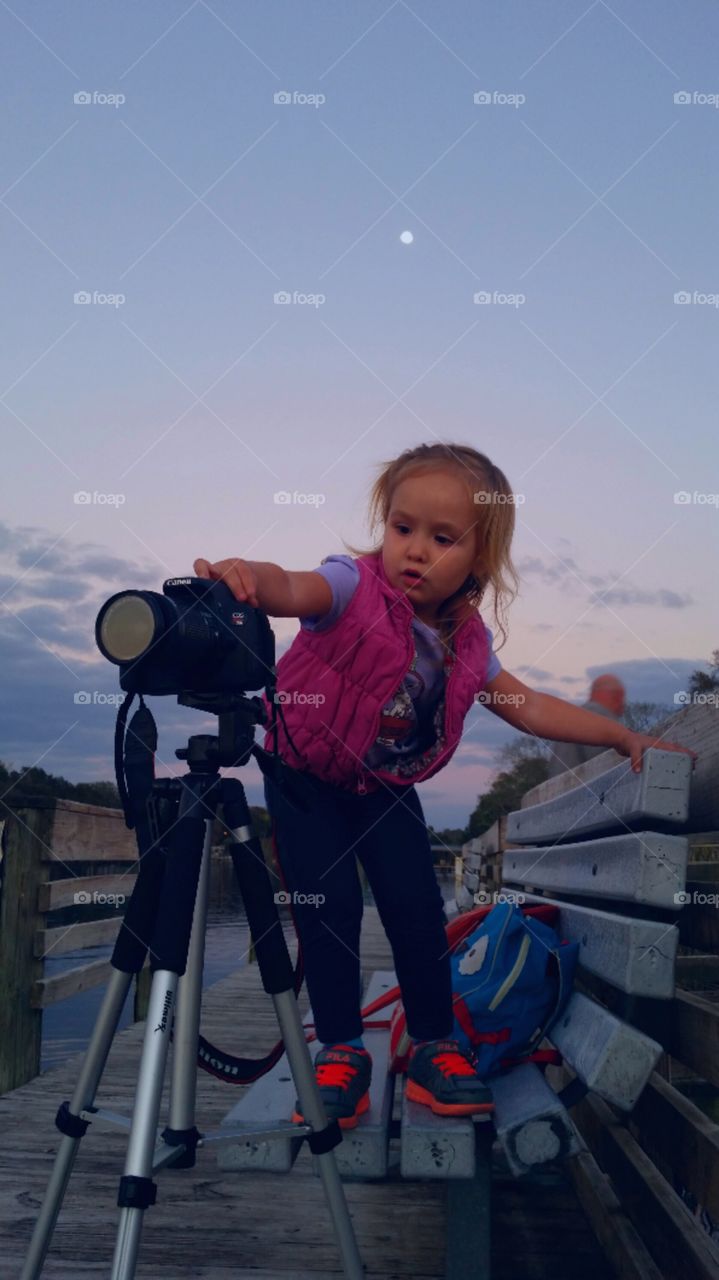 Girl standing on bench near binocular