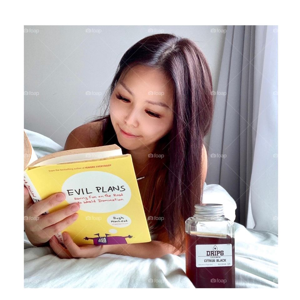 Asian female reading book with cold brew