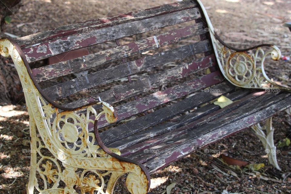 A rusted old chair, sitting on leaves and dirt and beautiful land in a bushland property