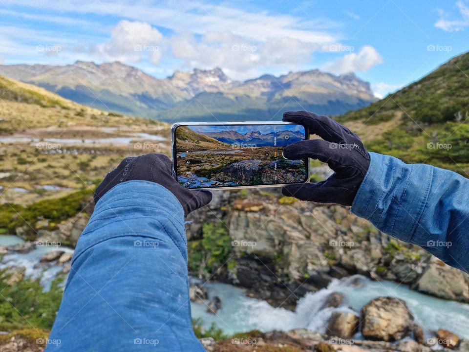 a photo of a person holding his cell phone and taking a photo of the landscape