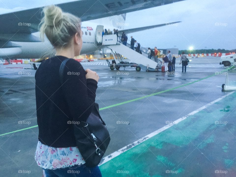 Woman in her 30 s getting on a plane at Gatwick airport in London.