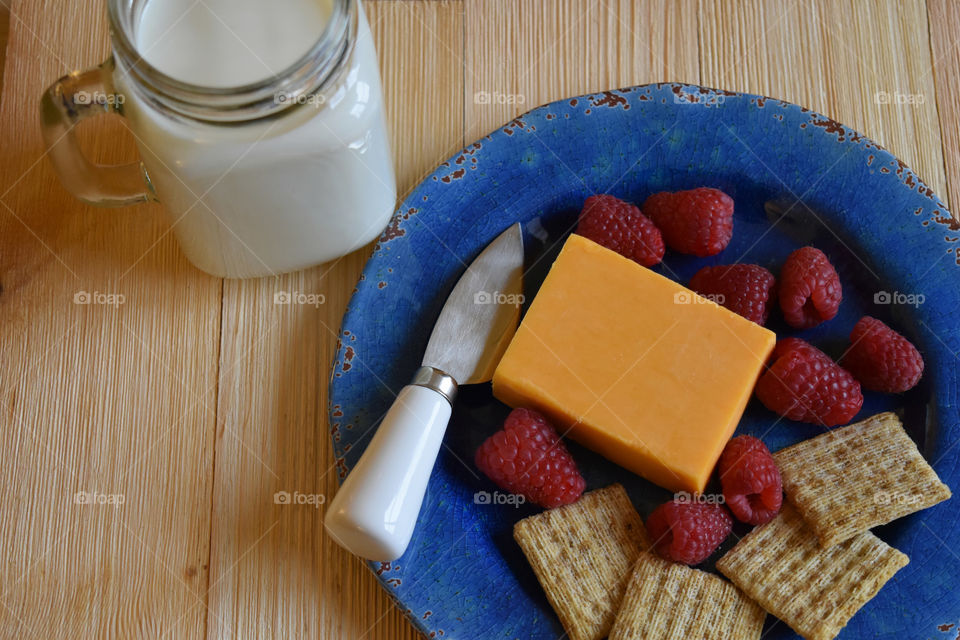 Cold glass of milk with plate of fruit and cheese