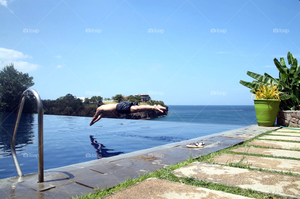 Man diving in infinity pool with an overlooking view