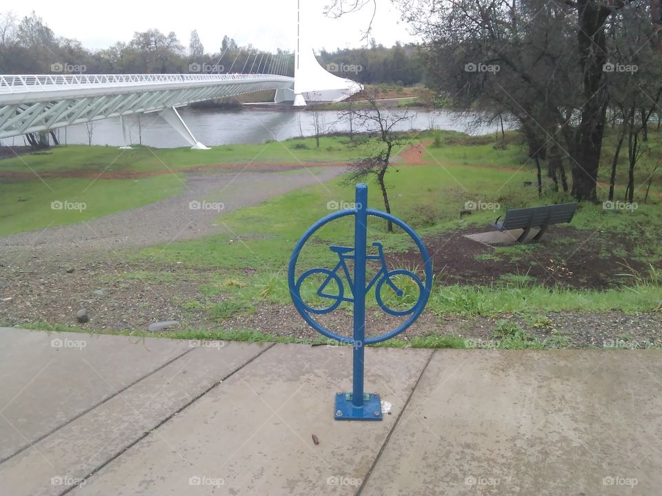 a shot of the Sundial Bridge, from a nearby path with an informational metal piece indicating that bike riding is allowed