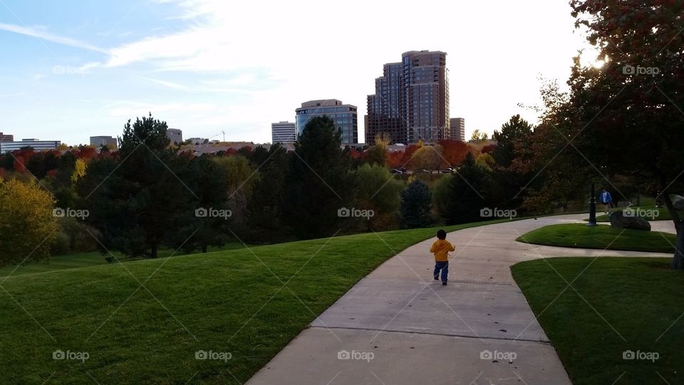 Little boy running in Denver, Colorado park in autumn