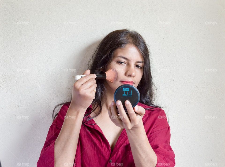 Woman applying compact powder on her face.