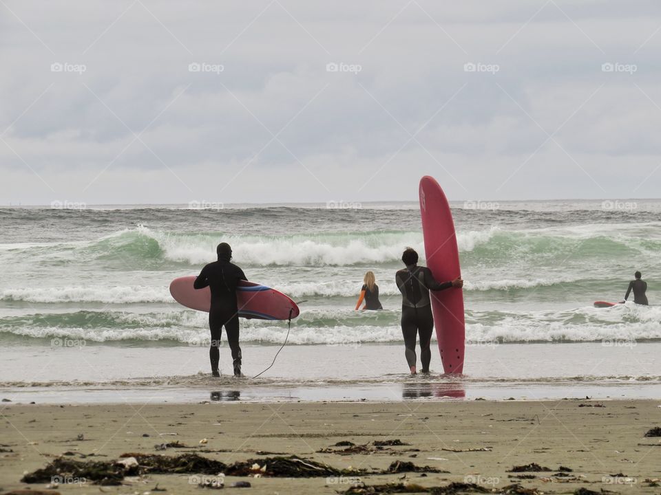 Two unknown surfers eying the waves at cox bay in Tofino British Columbia
