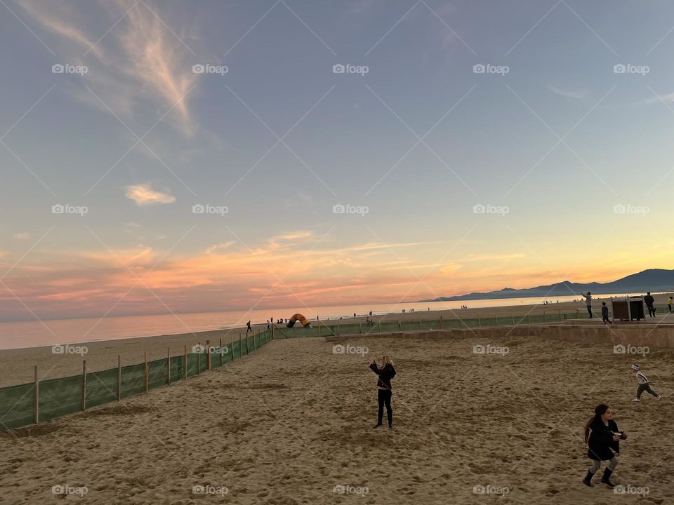 Beneath a stunning sunset, a figure captures the perfect moment on the beach, freezing the magic of the scene with their camera. 🌅✨