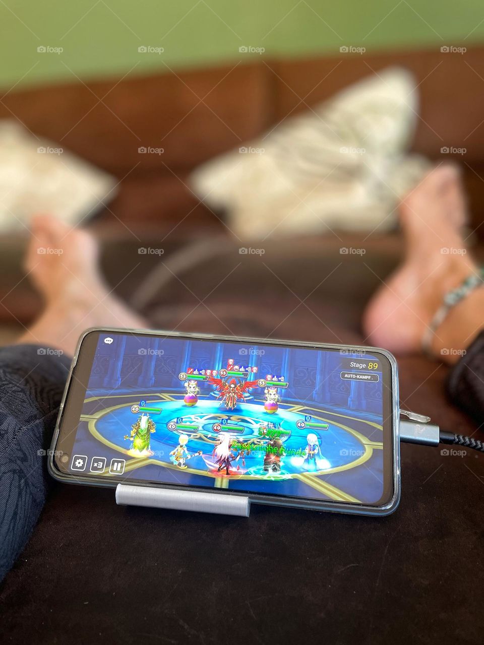 Video game on the cell phone between legs on the couch