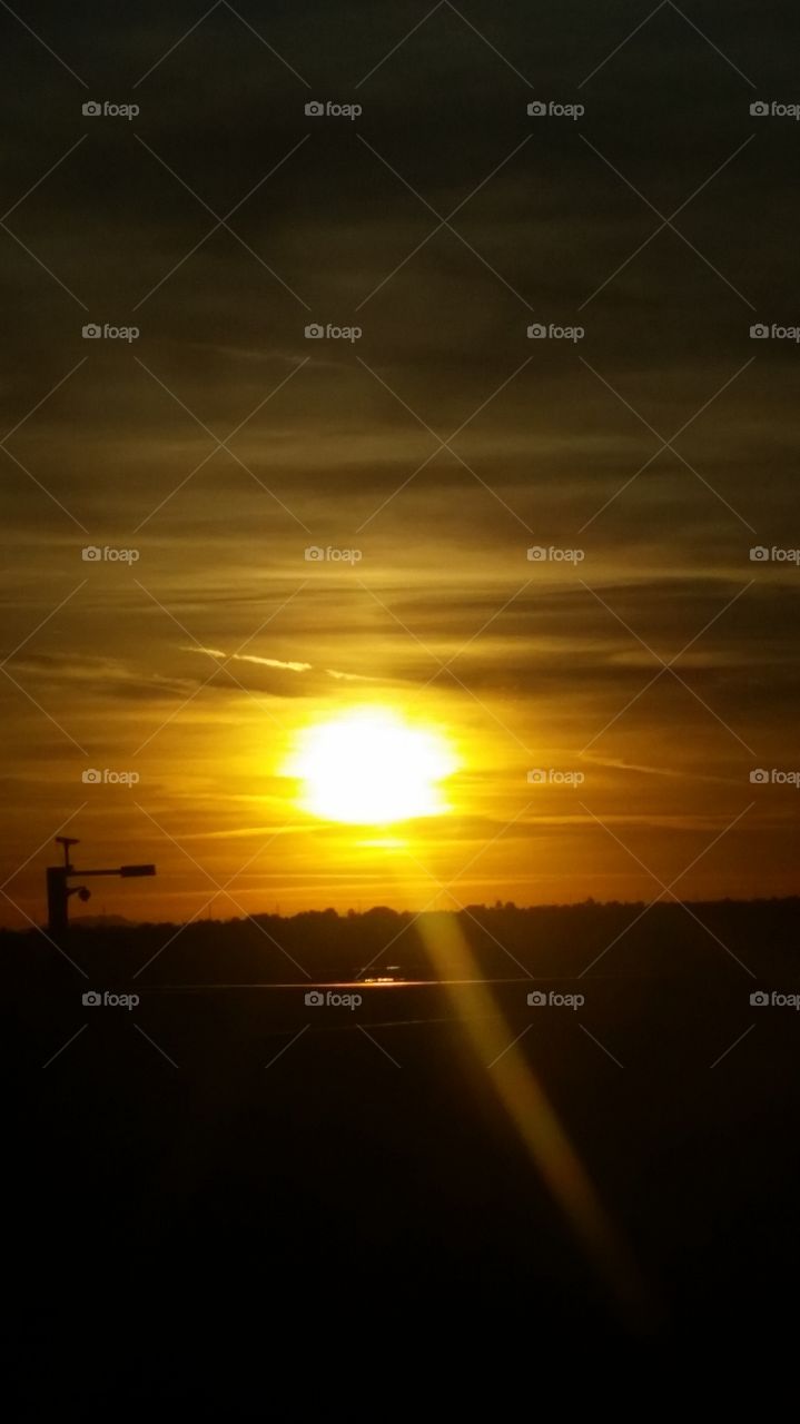 A Glorious sunset , in colors of Gold.
With Earthly  dark tones.  Any sunset
Is worth looking at .  Seems So Sireen. 
So calm to end a day , with a sunset 
In the Yonder Way.