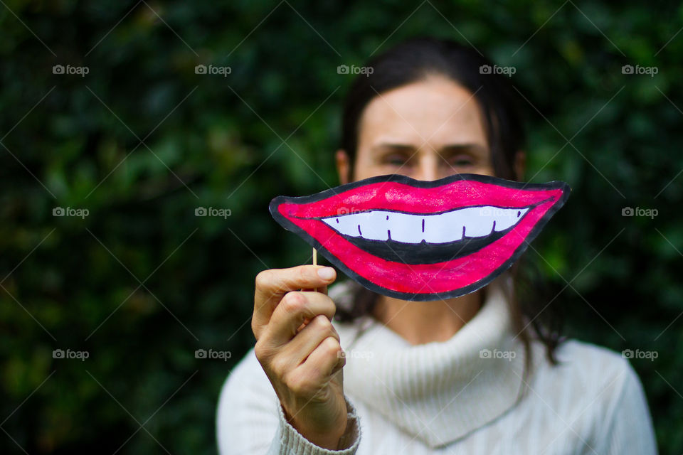 Smile! Woman holding oversized paper smiling mouth by her face. Fun at home.