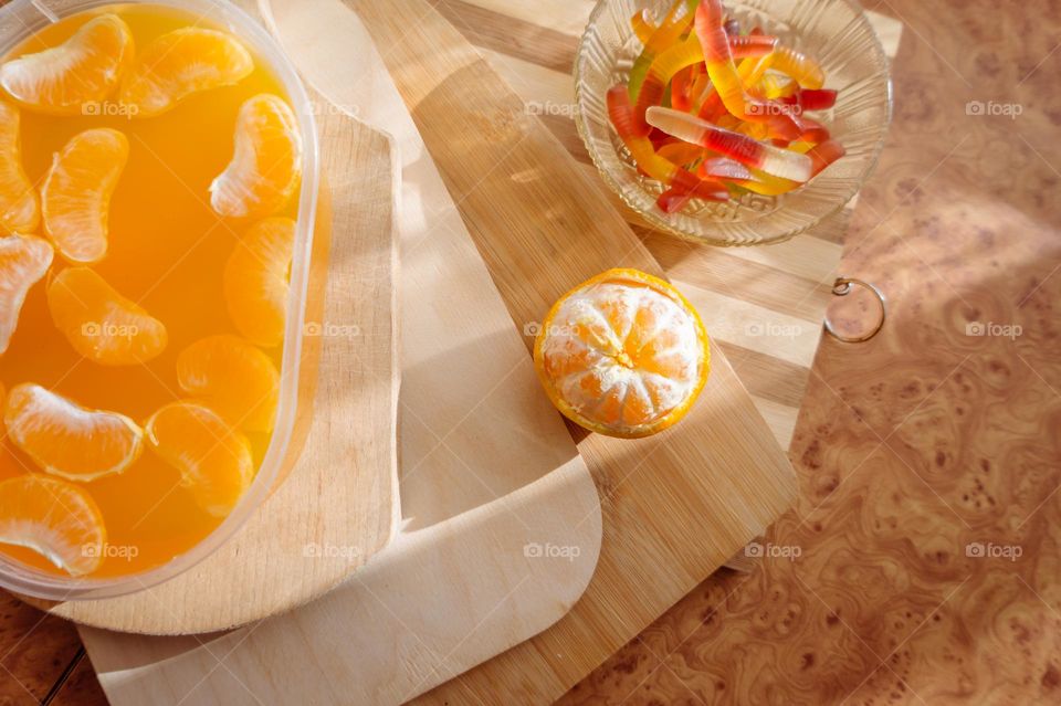 Delicious orange jelly with tangerine slices in a container and jelly worms.