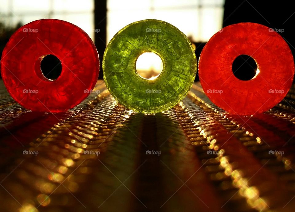 Orange red and green Lifesaver candies with light shining through a window