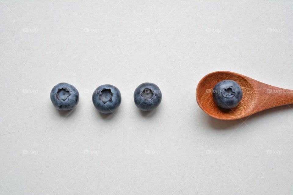 blueberries and wooden spoon on a white background top view, minimalistic lifestyle