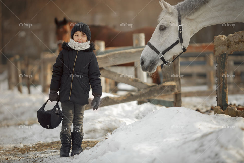 Little girl with horse on paddock 