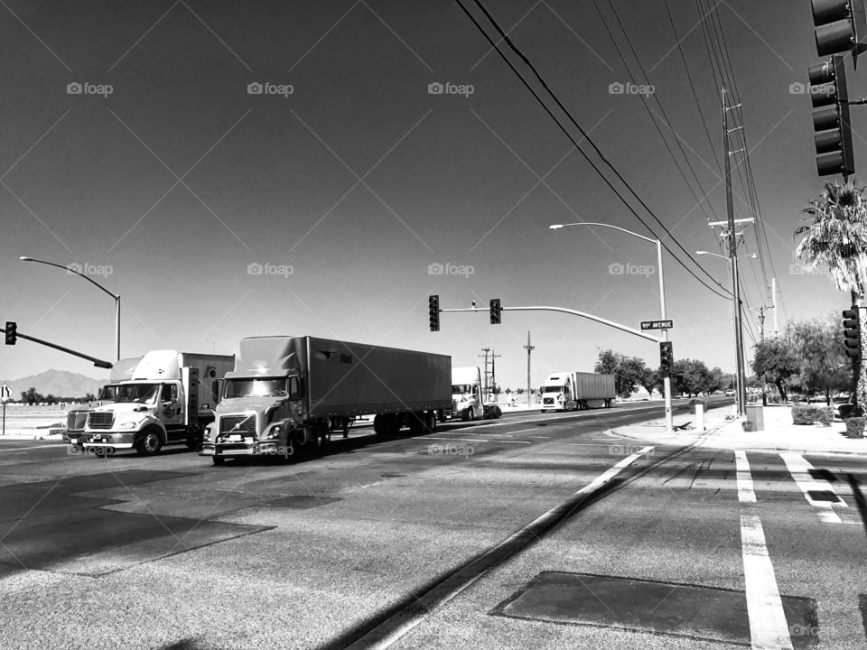 Semi trucks going through a signalized intersection. 