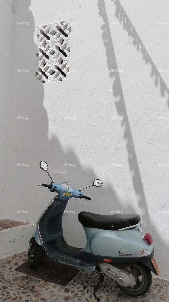 The vintage scooter "vespa" in a narrow street of a white Spanish village