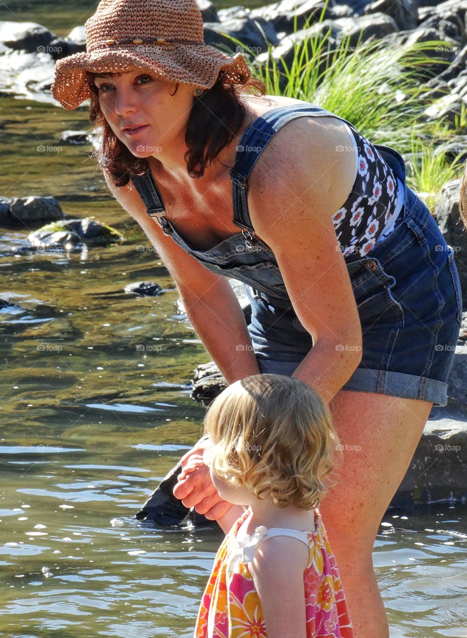 Mother And Daughter. Mother And Daughter Exploring The Shallow Bank Of A River
