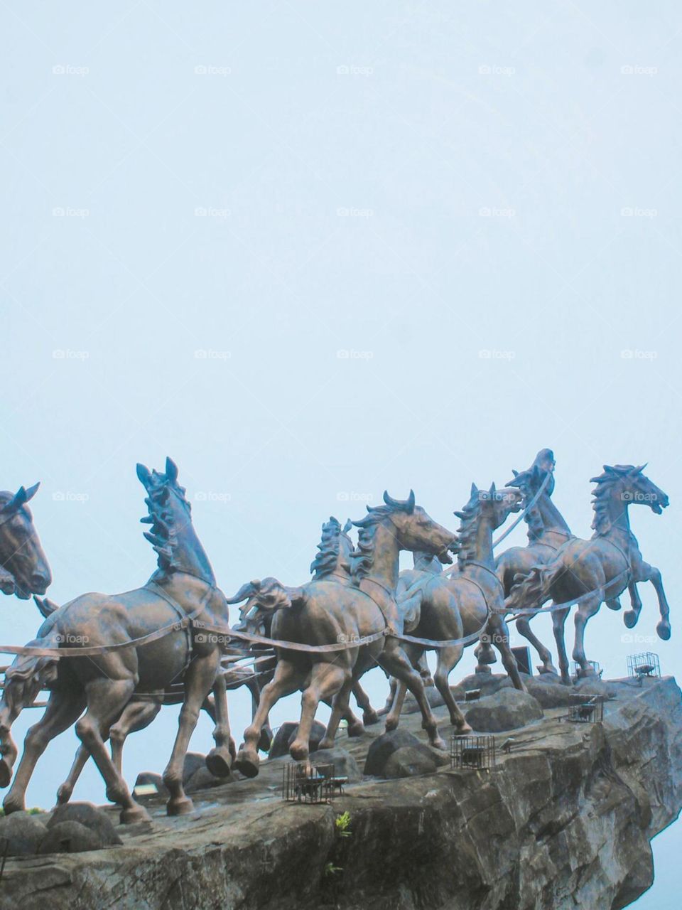 Close-up of a statue of a running horse on a large rock in low angle view