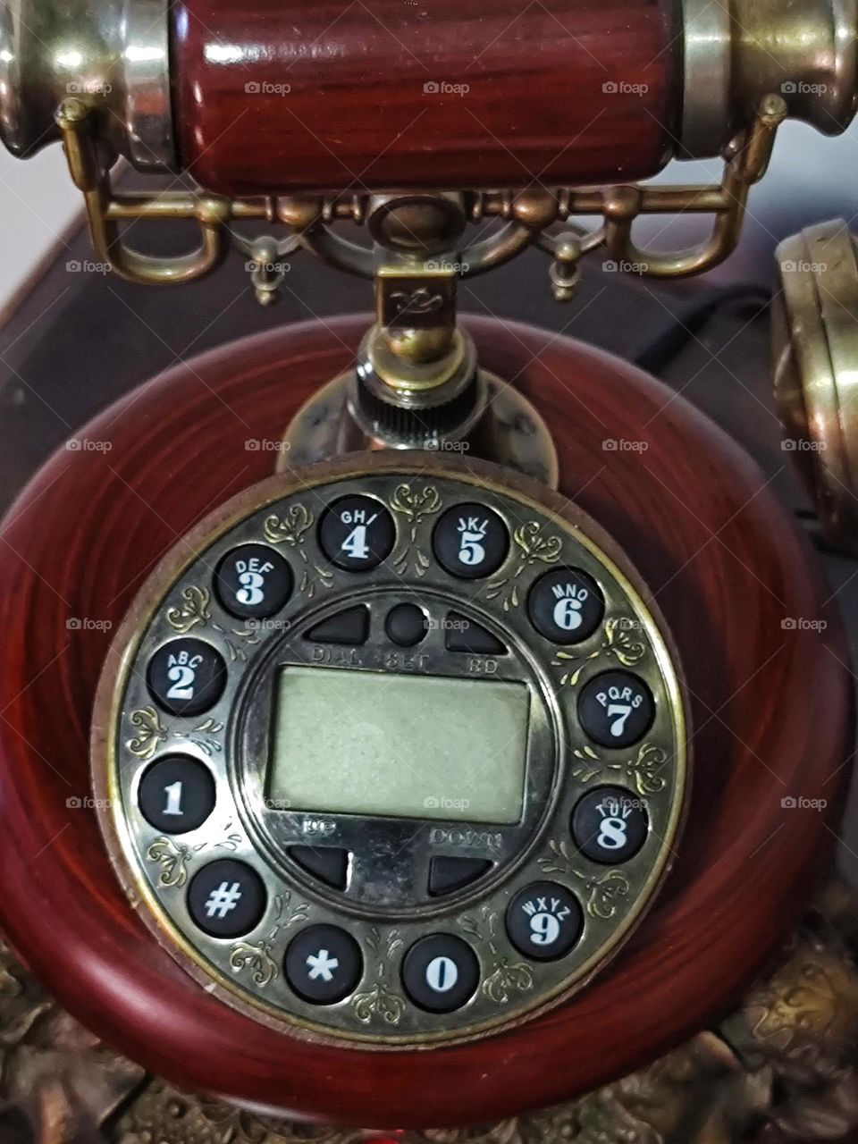 A very old telephone model with its circular wooden base, as well as the most modern cell phones, continues to make and receive calls.