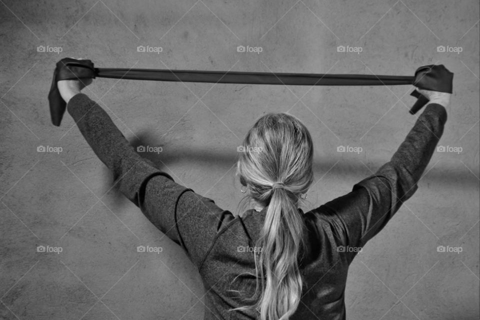 Rear view of a woman doing gymnastics with a resistance band